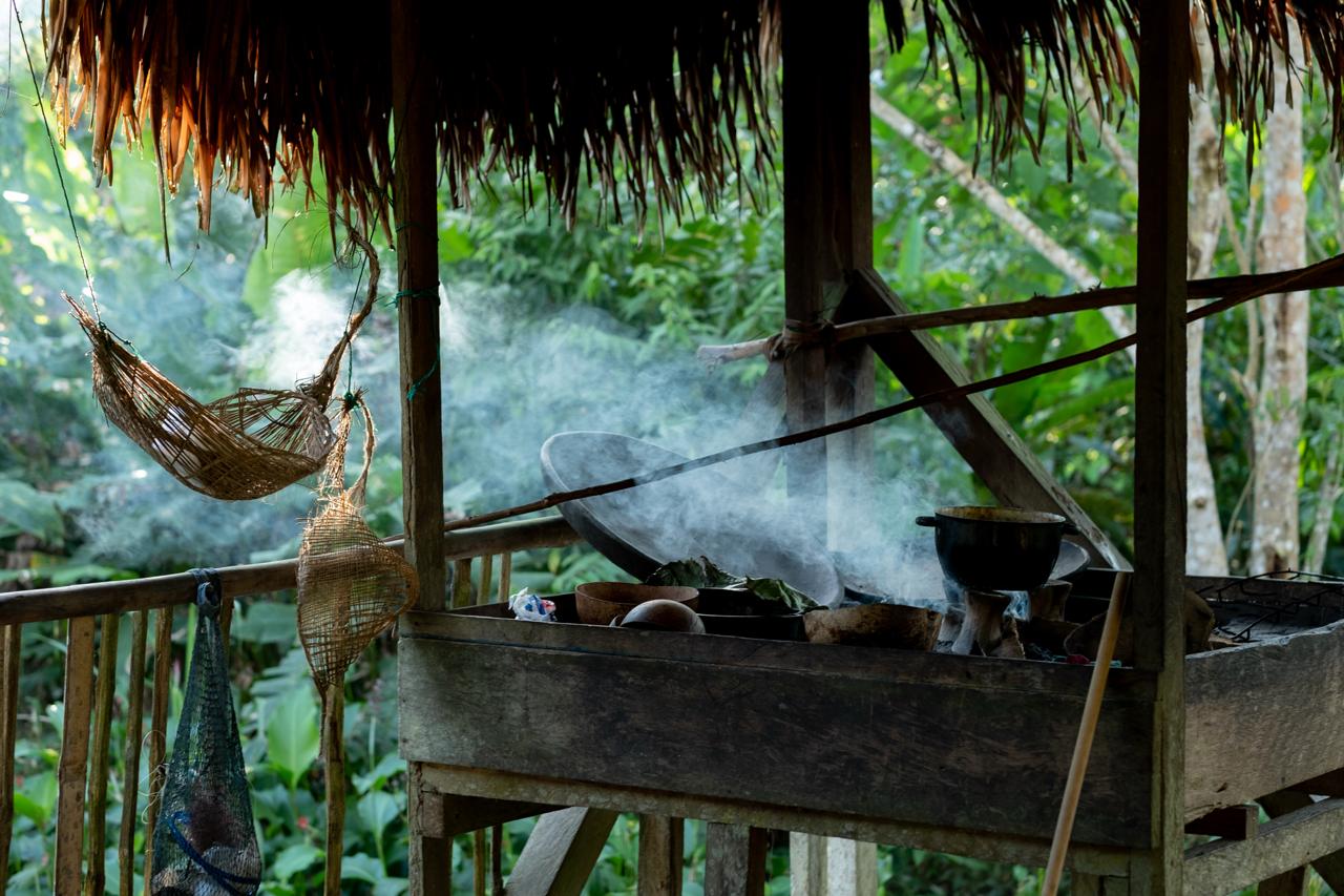 Smoke rising from a cooking fire under a thatched roof