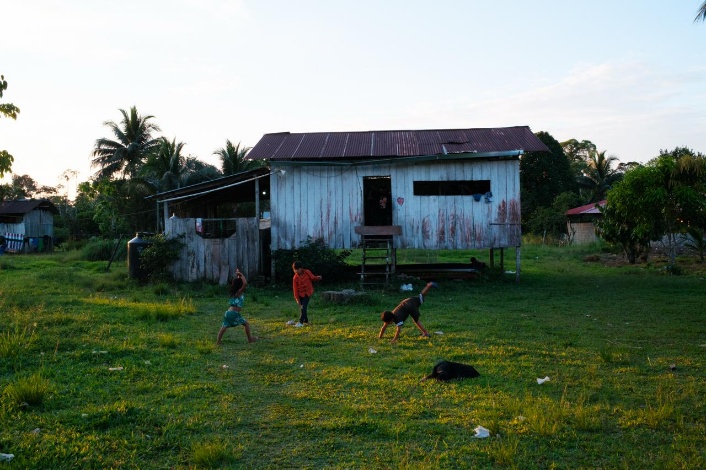 Children playing outside a wooden house